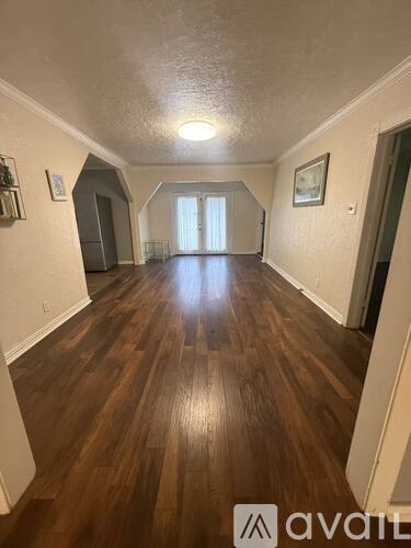 A long hallway with wood floors and a light at the end.