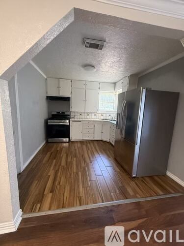 A kitchen with wooden floors and a refrigerator.