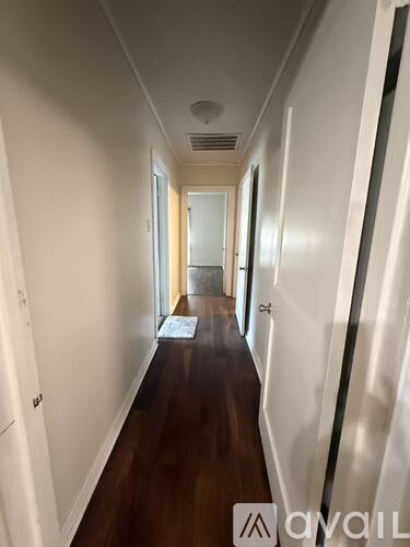 A long hallway with a mat on the floor and doors on both sides.