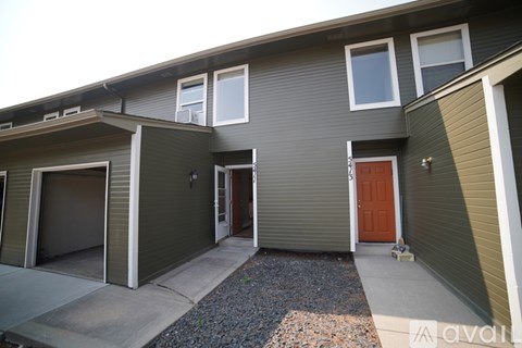 A house with a brown door and a grey wall.