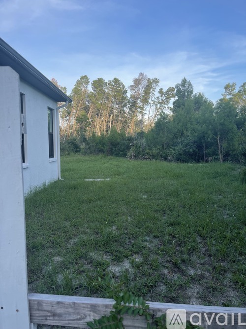 A white building with a sign that says "available" in front of a grassy field.
