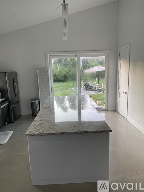 A kitchen with a marble countertop and a view of a backyard through a sliding glass door.