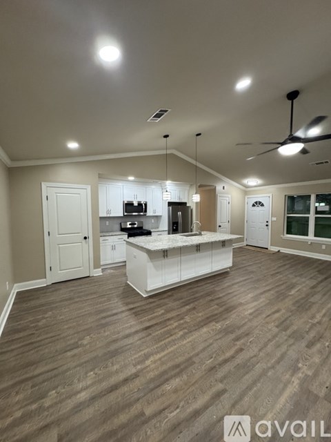 A spacious kitchen with white cabinets and a wooden floor.