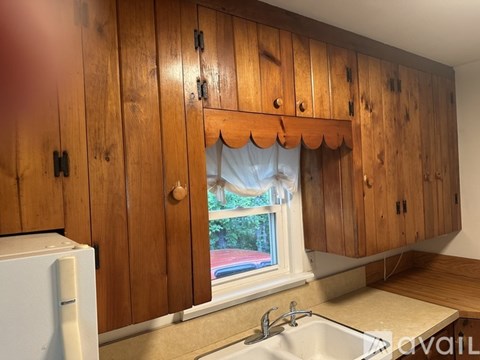 A kitchen with wooden cabinets and a window with a blue curtain.
