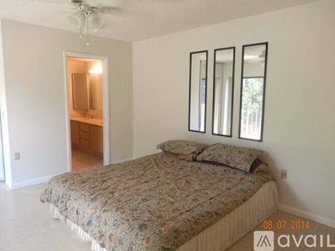 A bedroom with a bed, mirrors, and a ceiling fan.