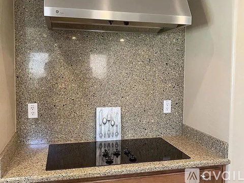 A kitchen counter with a granite top and a stainless steel range hood above it.