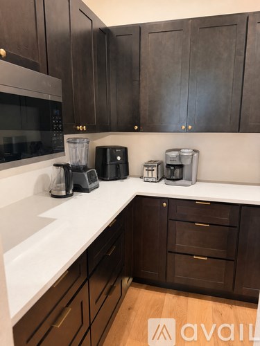 A kitchen with dark wood cabinets and white countertops.