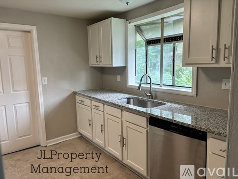 A kitchen with white cabinets and a granite countertop.