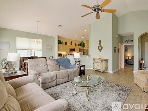 A living room with a glass coffee table and a beige couch.