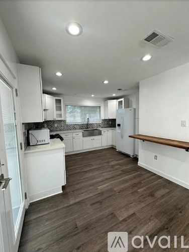 A kitchen with white cabinets and a wooden floor.