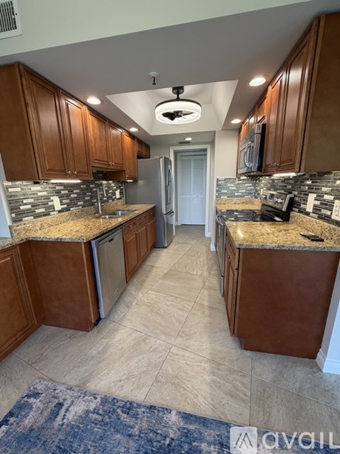 A kitchen with brown cabinets and granite countertops.