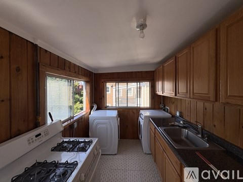 A kitchen with wooden cabinets and a white stove top oven.