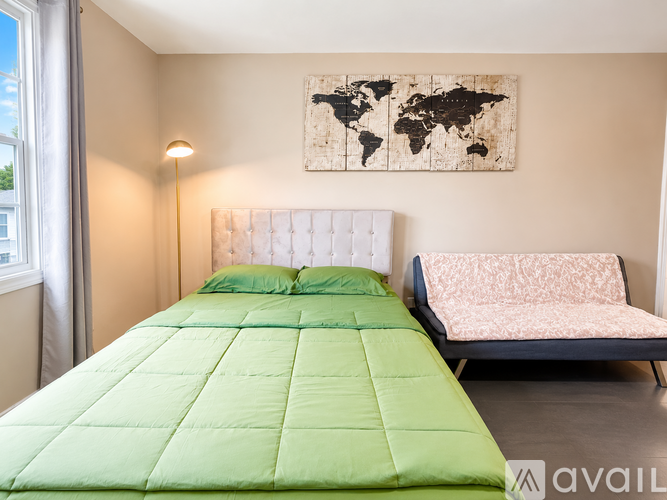 A bedroom with a green bed and a world map on the wall.