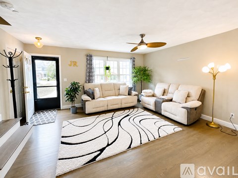 A living room with a rug on the floor and a couch in the middle.