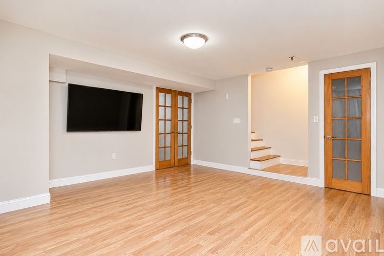 A spacious room with wooden floors and a staircase leading to another room.