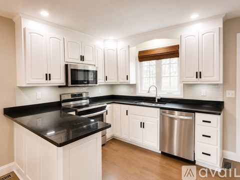 A kitchen with white cabinets and black countertops.