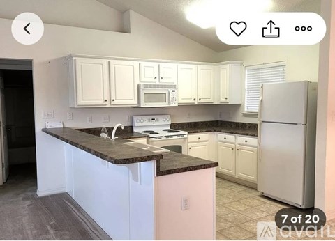 A kitchen with white cabinets and a pink island.