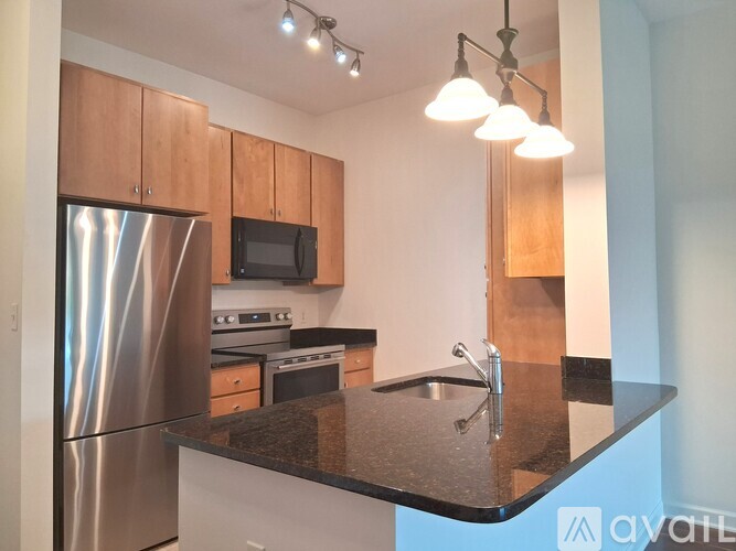 A kitchen with a black granite counter top and stainless steel appliances.