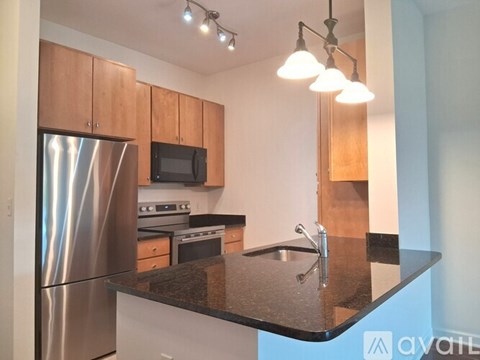 A kitchen with a black granite counter top and stainless steel appliances.