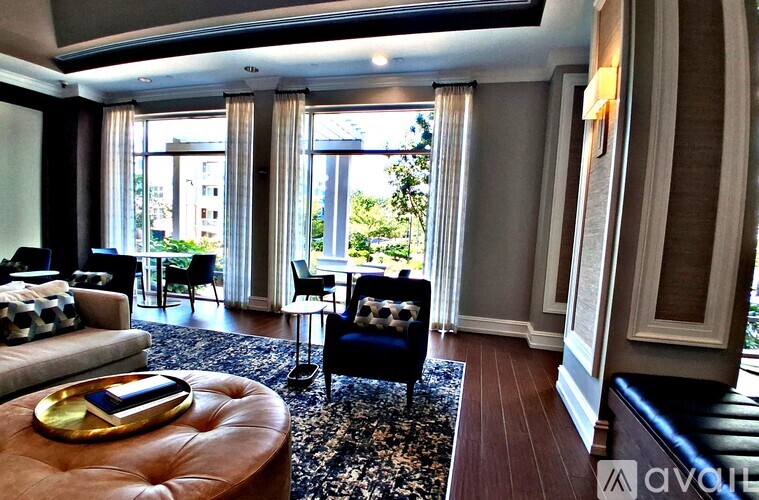 A living room with a brown ottoman and a black and white patterned rug.
