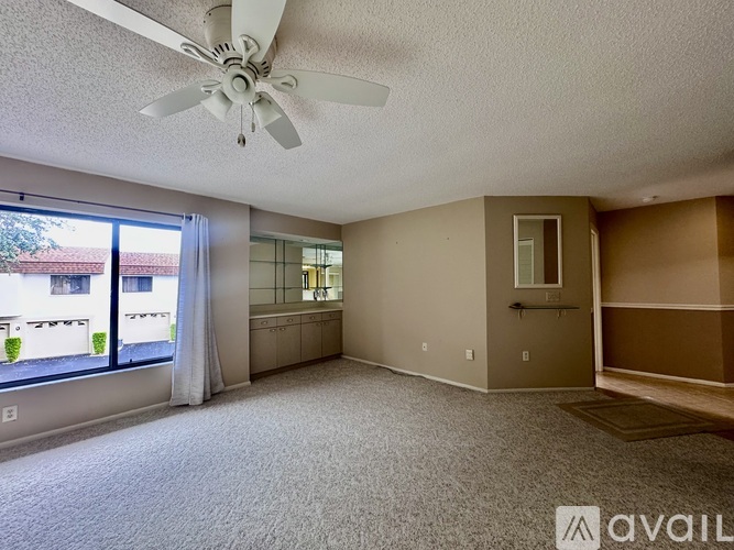 A spacious living room with a ceiling fan and sliding glass doors.