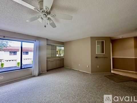 A spacious living room with a ceiling fan and sliding glass doors.