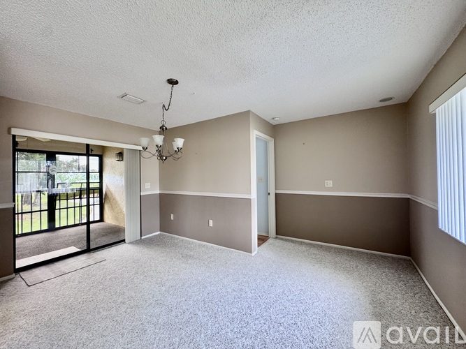 A spacious room with a chandelier and sliding glass doors.