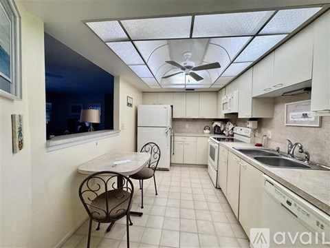 A kitchen with a table and chairs and a fan on the ceiling.