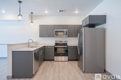 A modern kitchen with stainless steel appliances and wooden flooring.