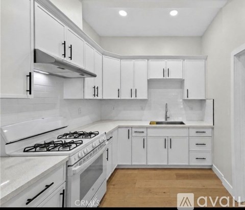 A kitchen with white cabinets and a stove top oven.