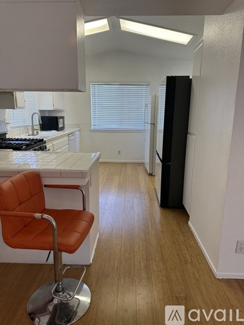 A kitchen with a white counter top and a red chair.