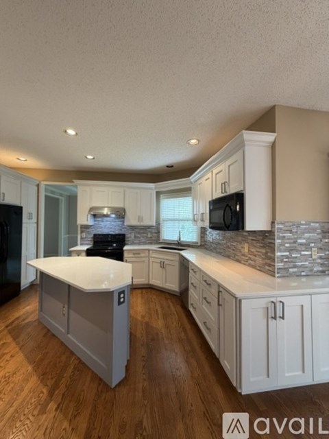 A kitchen with white cabinets and a wooden floor.