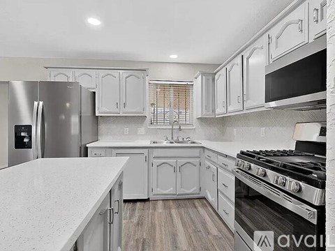 A kitchen with white cabinets and a stainless steel refrigerator.