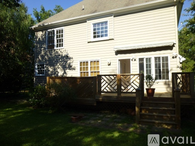 A house with a deck and a tree in front.