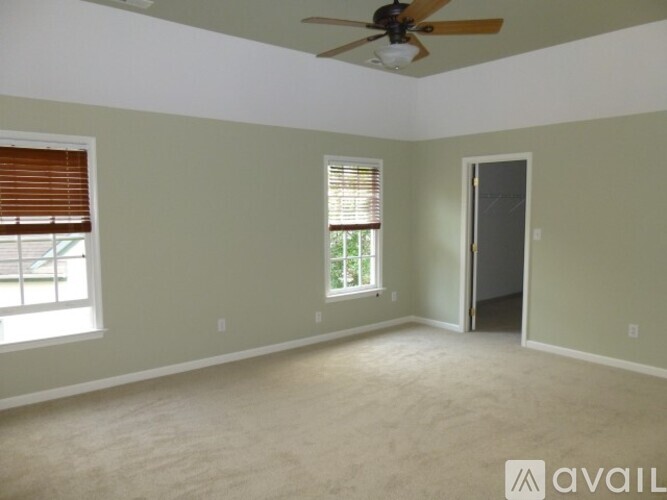 A room with a ceiling fan and two windows.