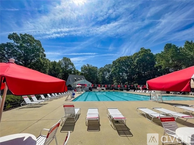 A pool surrounded by red umbrellas and lounge chairs.