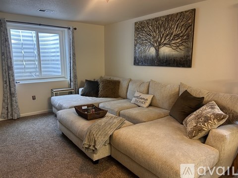 A living room with a large couch and a painting on the wall.
