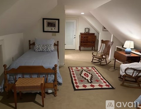 A bedroom with a bed, chair, and rug.