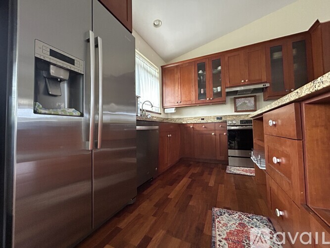 A kitchen with a stainless steel refrigerator and wooden cabinets.