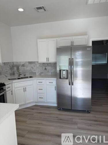 A kitchen with a stainless steel refrigerator and white cabinets.