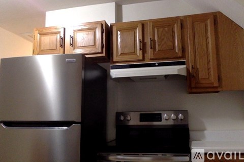 A kitchen with a stainless steel refrigerator and wooden cabinets.