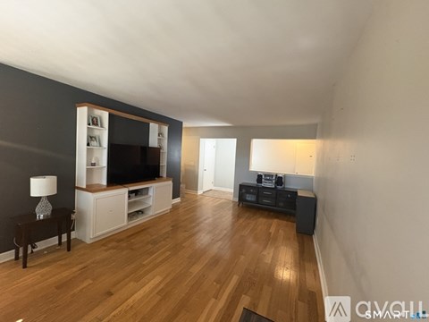 A living room with a wooden floor and a television on a stand.