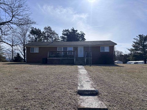 A small house with a porch and a yard with a white line painted on the ground.