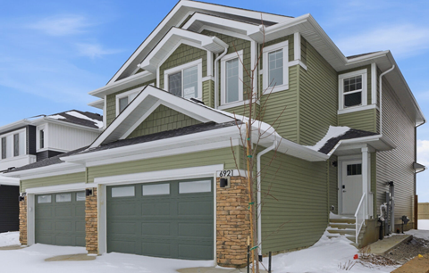 A house with a green garage door and a grey roof.