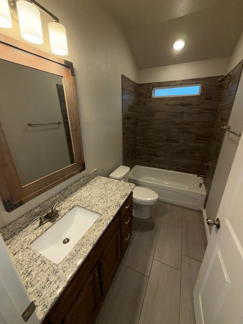 A bathroom with a sink, toilet, and a window.