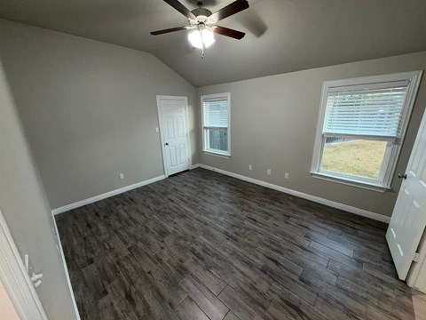 A room with a ceiling fan and wooden flooring.