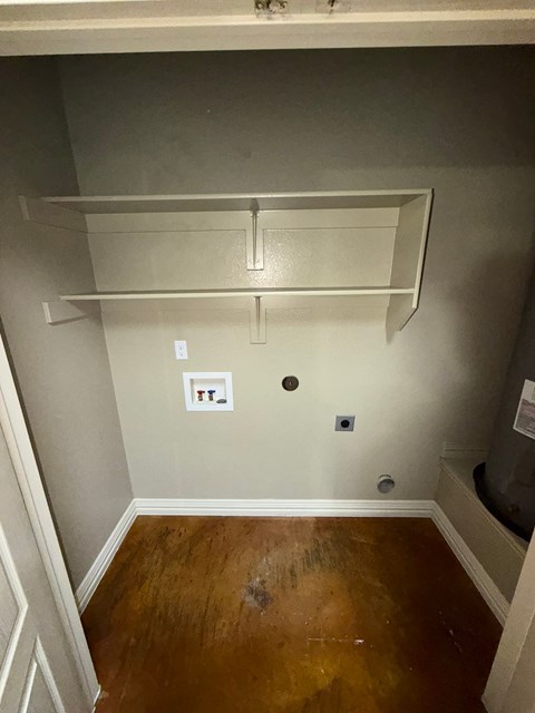 A white shelf is mounted on a wall above a wood floor.