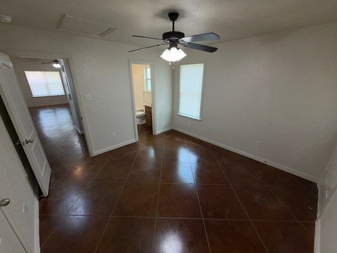 A room with brown tiles and a ceiling fan.