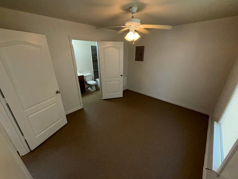 A room with a ceiling fan and two doors.