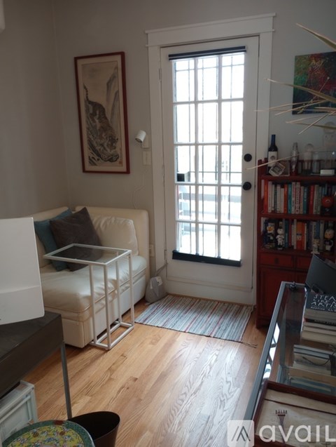 A living room with a white couch and a painting on the wall.